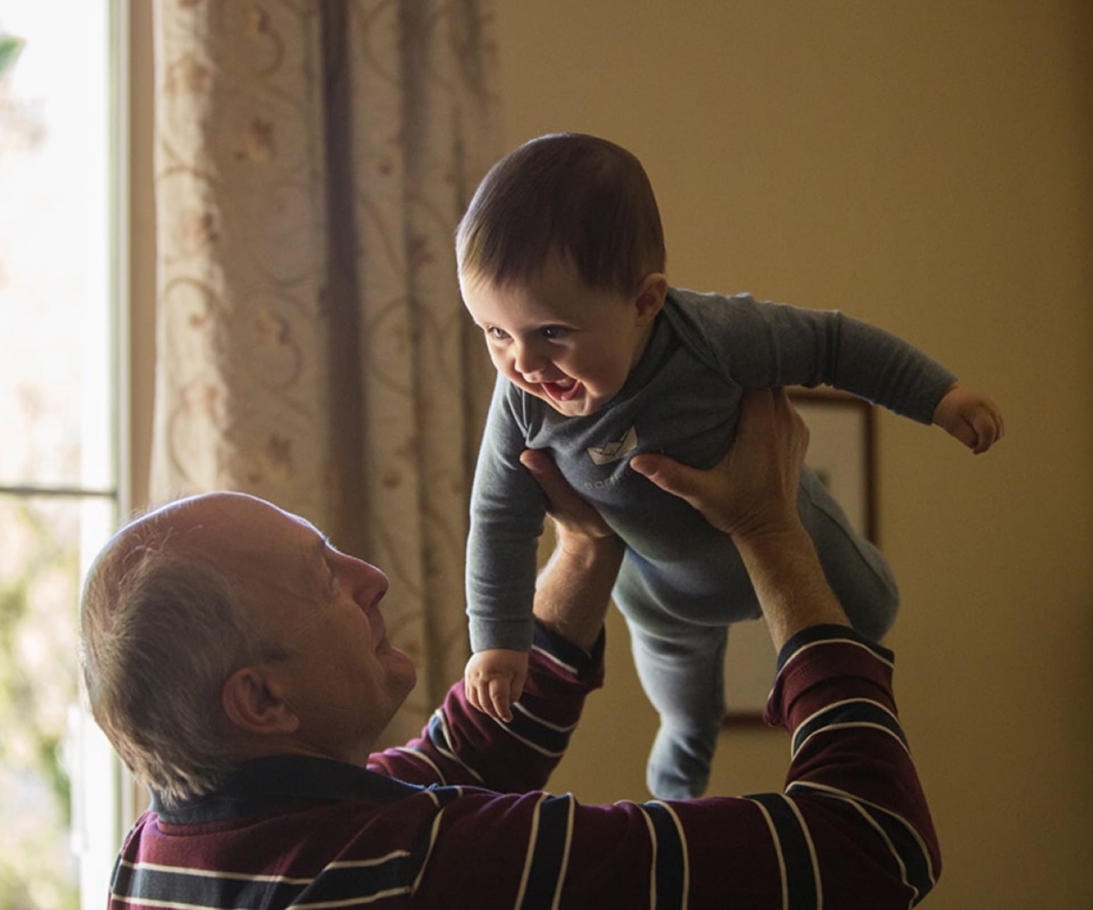 Man holding a laughing baby up in the air