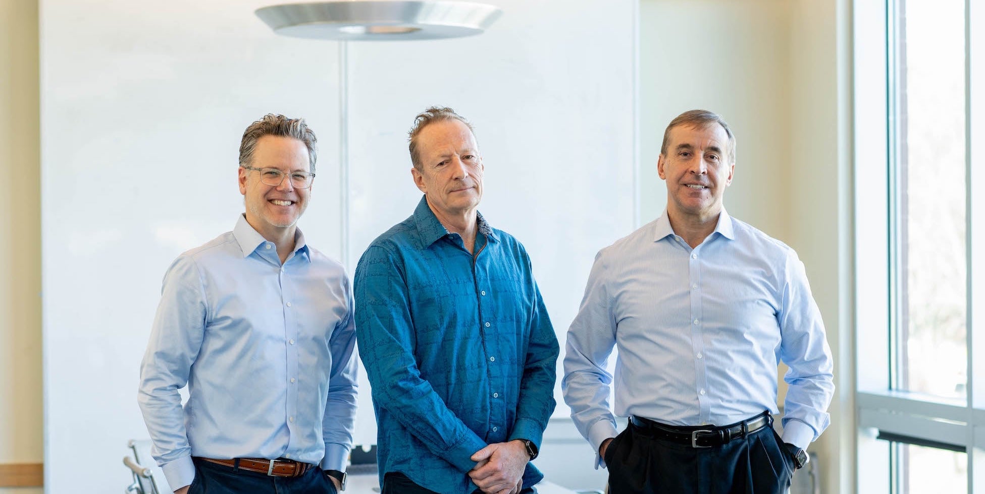 three men standing, looking at the camera, smiling